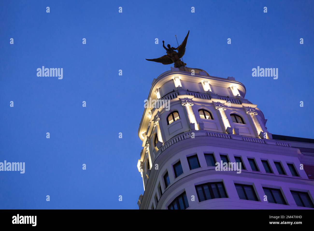 Night view of the tower of a building topped with a sculpture of a Phoenix bird. City of Madrid, Spain. Space for text. Stock Photo