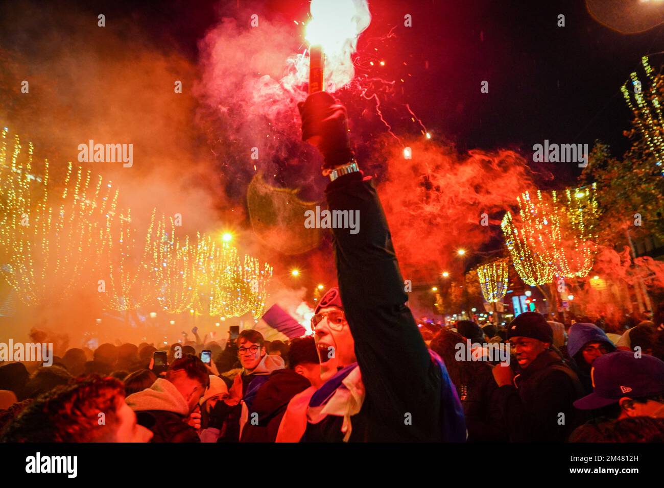 Paris, France. 19th Dec, 2022. A football fan holds a red firework in support of the French football team. French football fans gather on the Champs Elysees, Paris, to support their national team which they play against Argentina during the final of the FIFA World Cup Qatar 2022 on December 18, 2022. Argentina ultimately is crowned as the winner after winning 4-2 in penalties even though the two teams reach a draw 3-3 in extra time. Credit: SOPA Images Limited/Alamy Live News Stock Photo