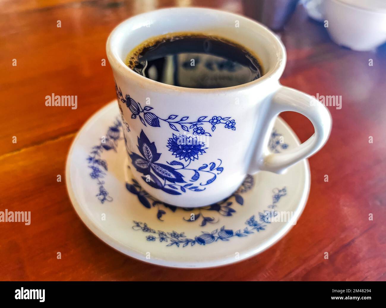 Blue and white cup pot with black coffee americano on wooden table in