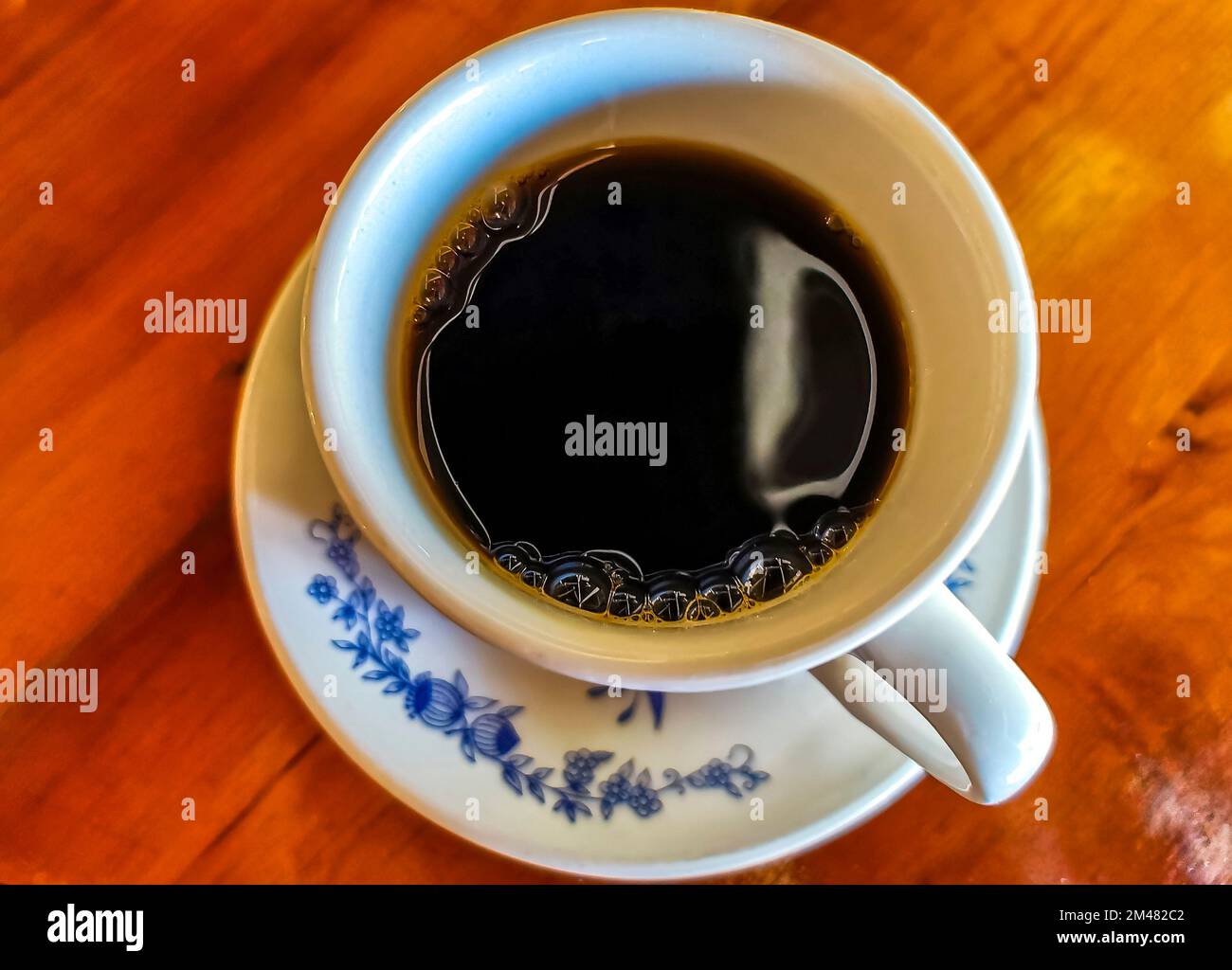Blue and white cup pot with black coffee americano on wooden table in
