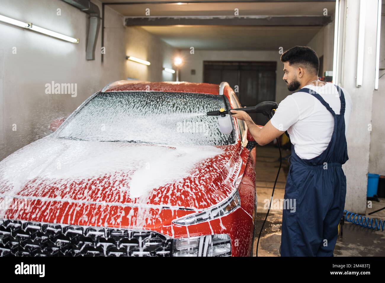 Portrait of young bearded man in working clothes, car wash employee