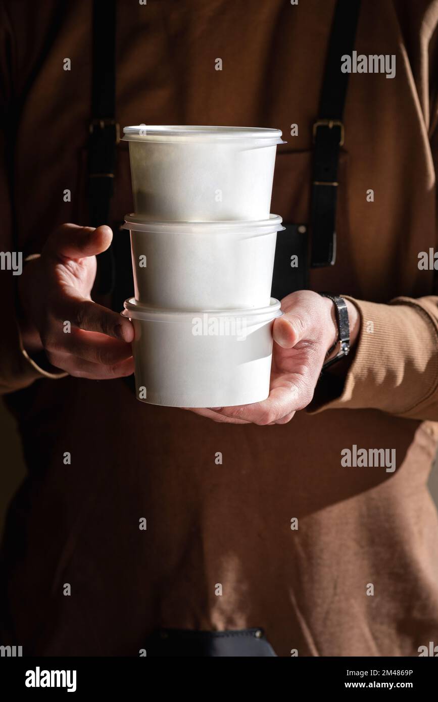 Stack of food delivery boxes. Anonymous hands holding stack of delivery boxes. Craft packaging