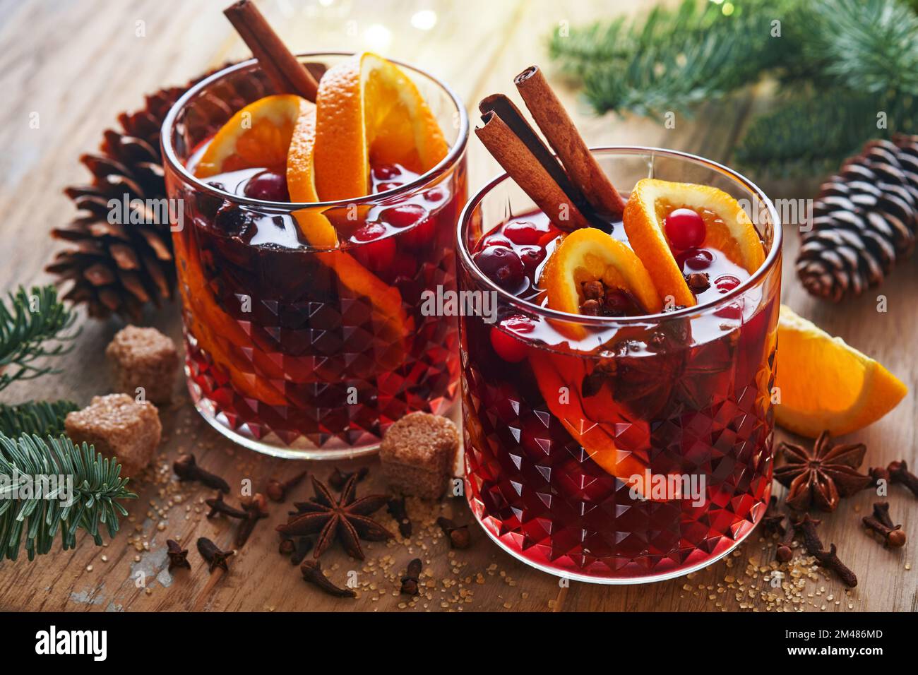 Christmas hot mulled wine. Glasses of mulled wine with aromatic spices cinnamon, anise, sugar and fir tree branches with bokeh and decorations. Tradit Stock Photo