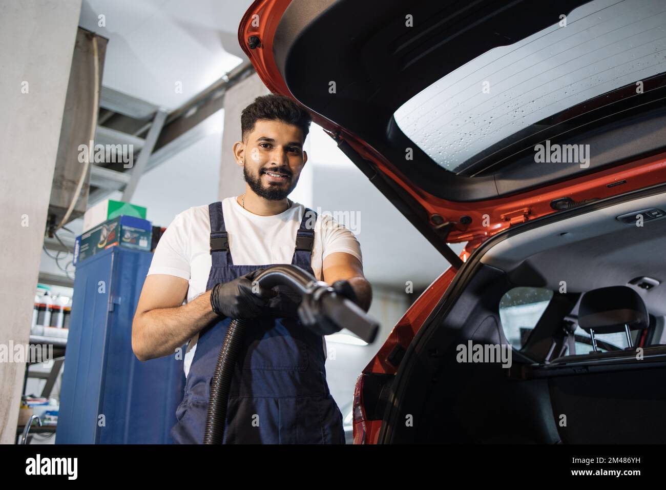 Car interior detailing concept. Young bearded man in uniform doing