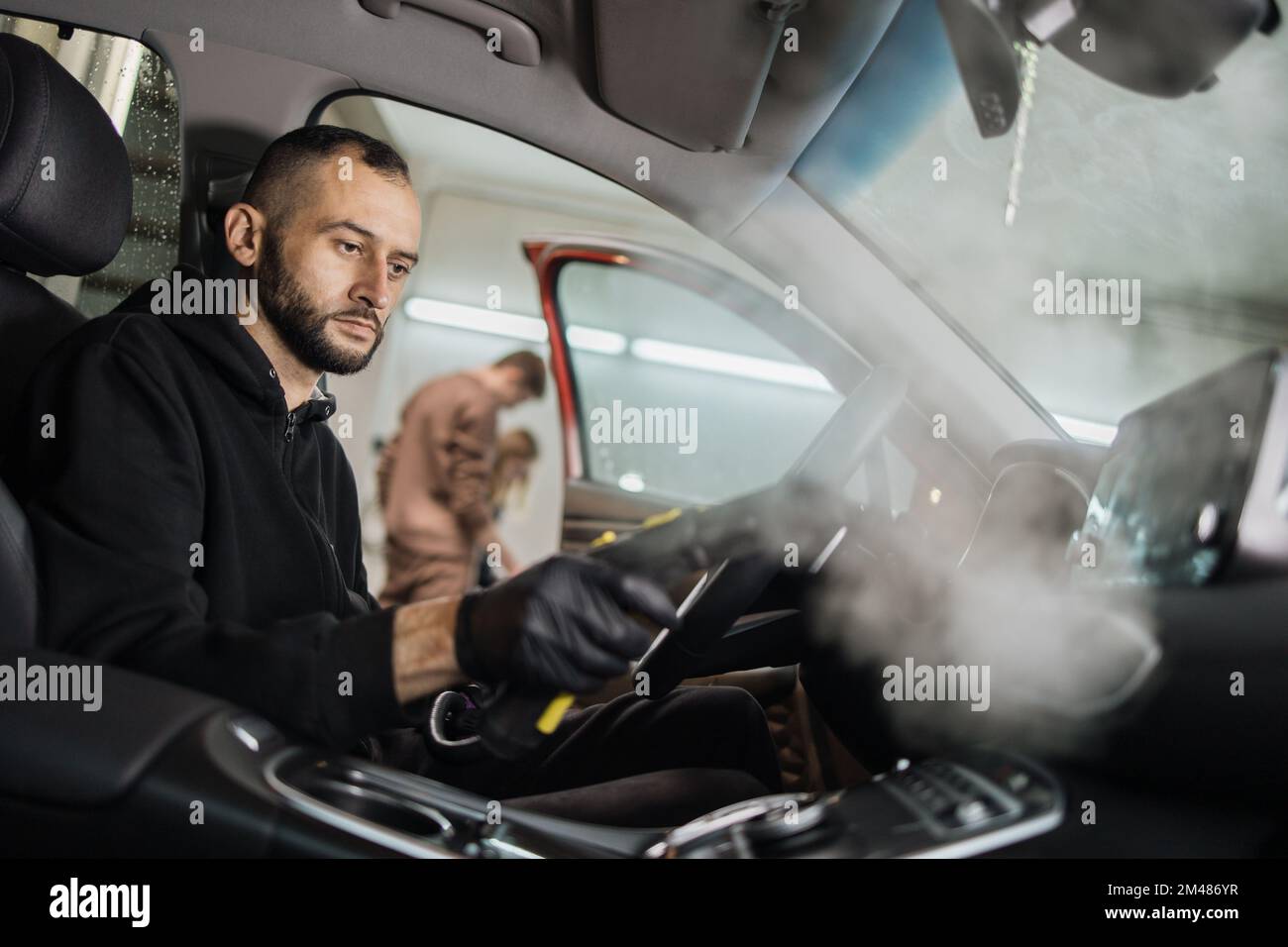 Cleaning of car salon with steam cleaner. Side view of professional
