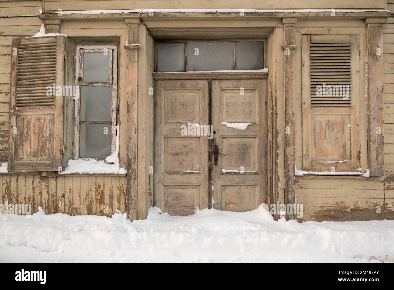 doors and windows of a very old house. snow in front of the house. winter. Stock Photo