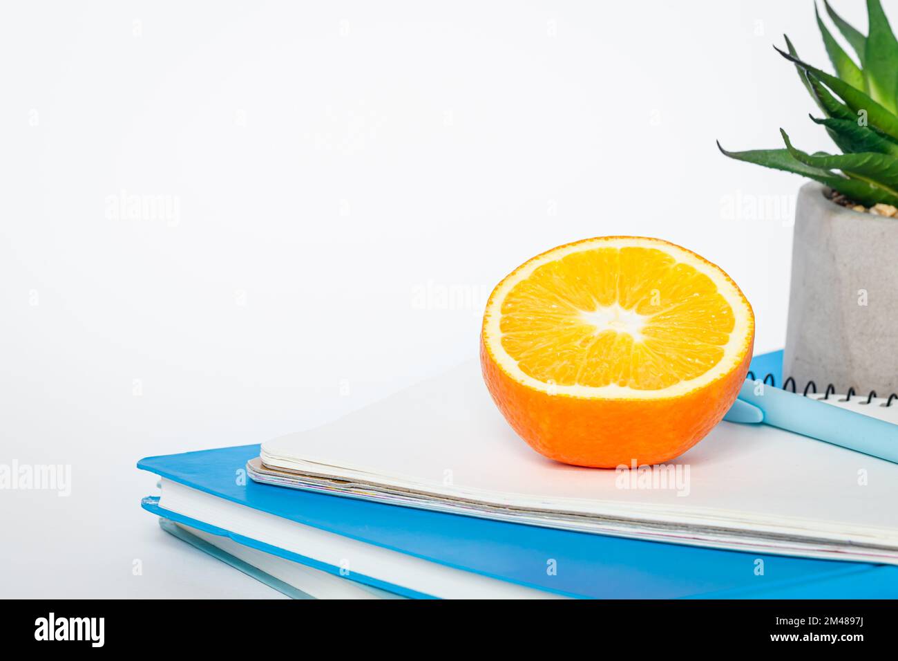 Notebooks and an orange on a white background, isolated, copy space. Stock Photo