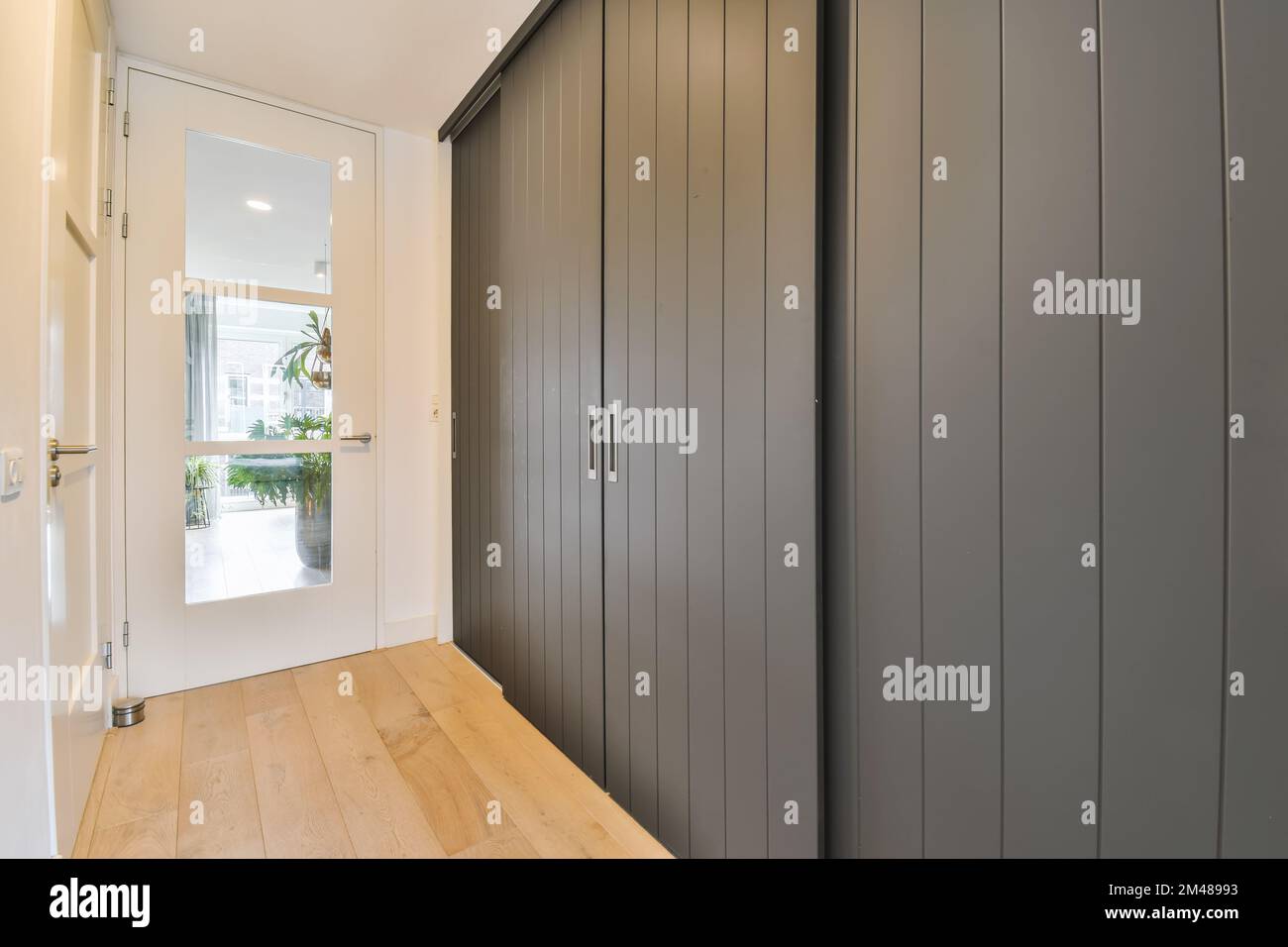 a hallway with wooden flooring and grey painted wall paneled panels on
