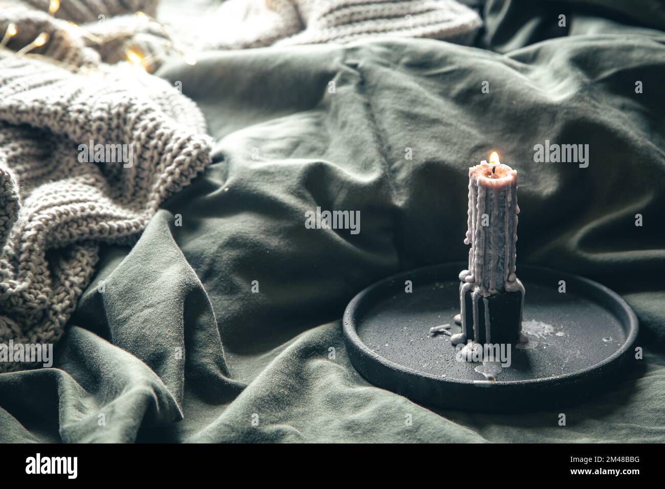 Beautiful burning candle in bed on a blurred background. Stock Photo