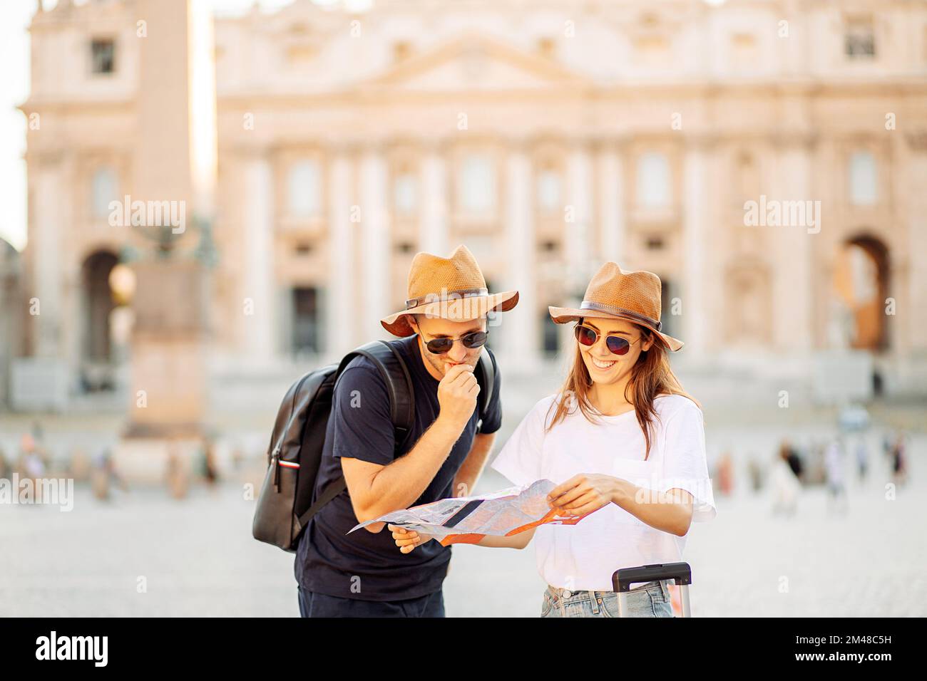 Happy tourists looking at a map and choose a hotel. Couple of tourists on vacation in Rome, Italy. Satisfied tourists looking for a direction on a map Stock Photo