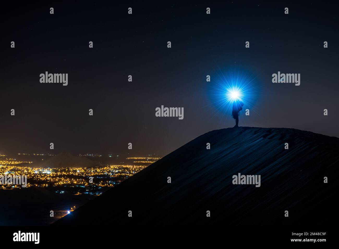 Silhouette of man standing on sand dune  with head torch, Huacachina, Peru, South America Stock Photo