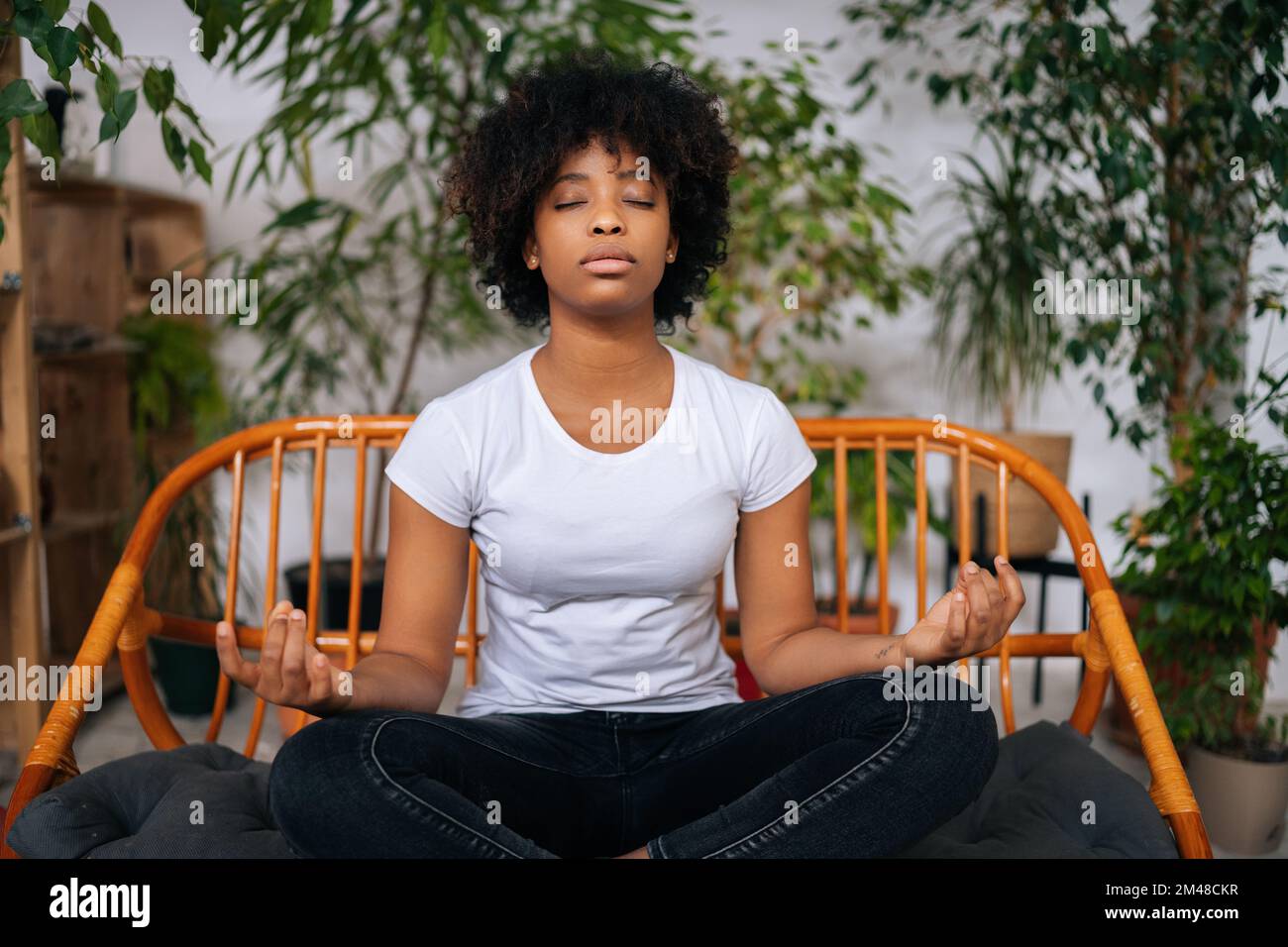 Portrait of peaceful black young woman sitting with closed eyes on sofa ...