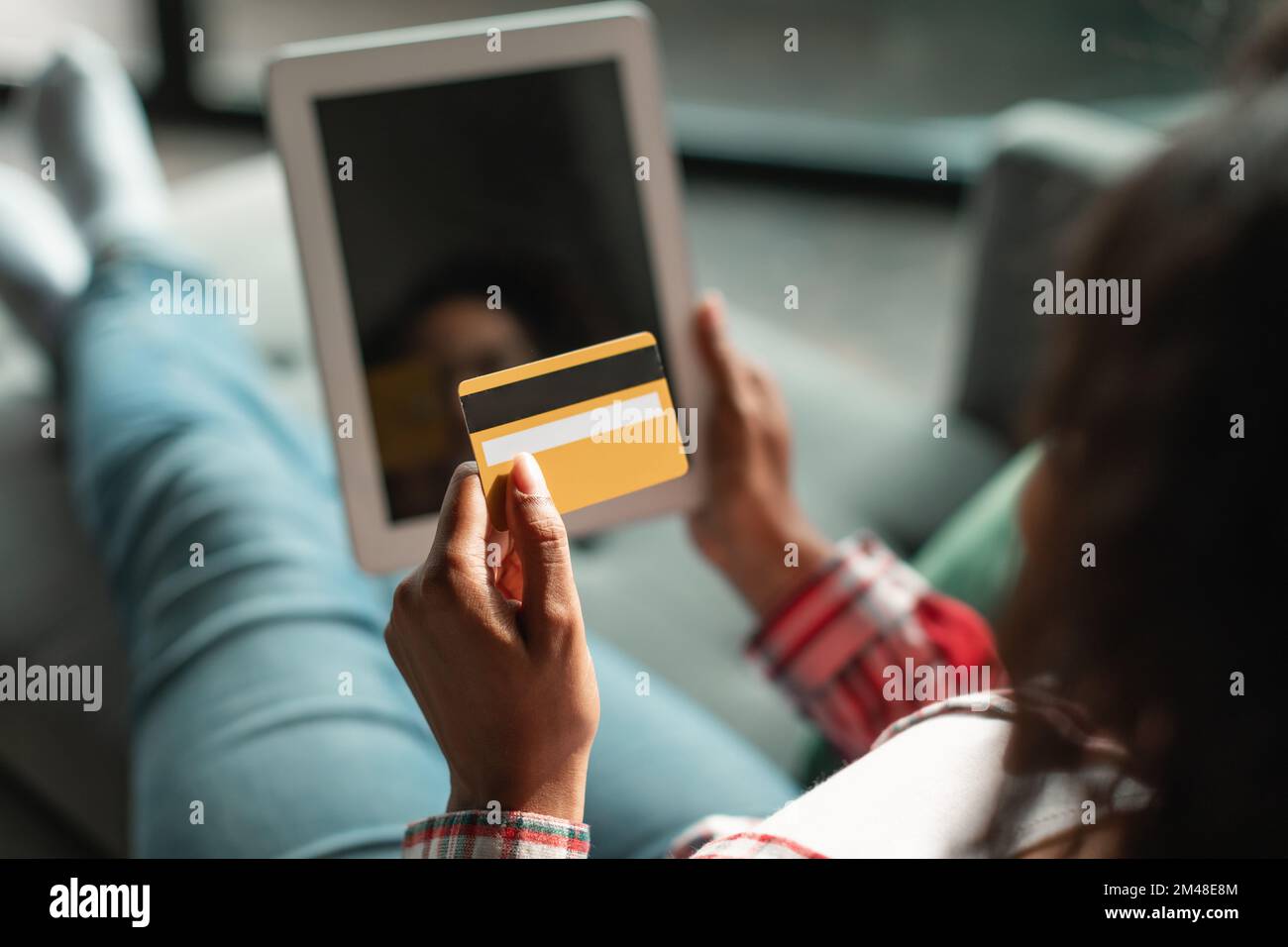 Busy millennial black female use credit card and tablet with empty