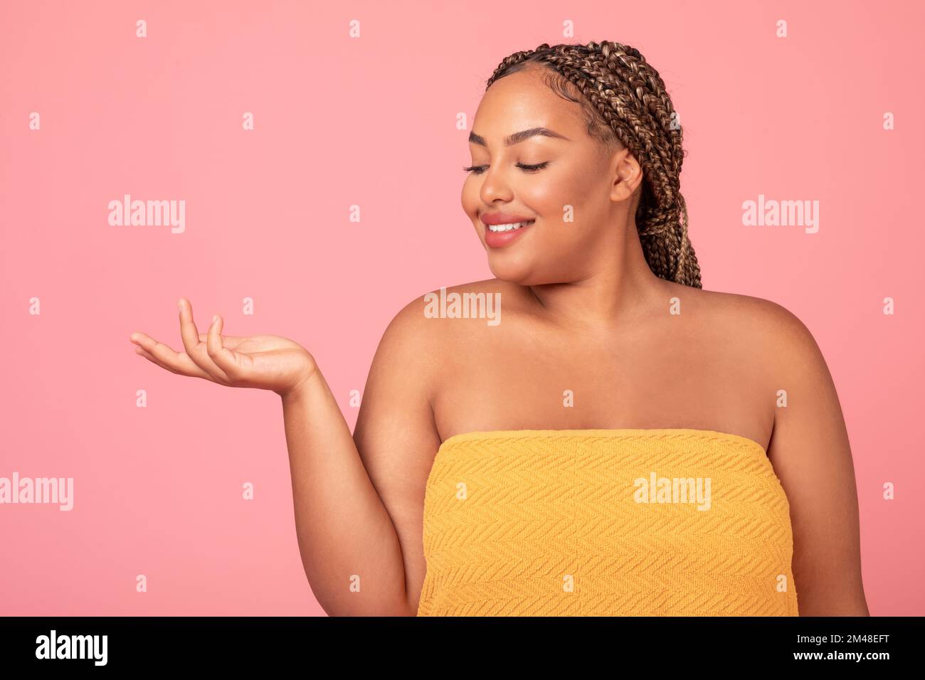 Beautiful black plus size lady holding invisible object, recommending new beauty product, free space Stock Photo