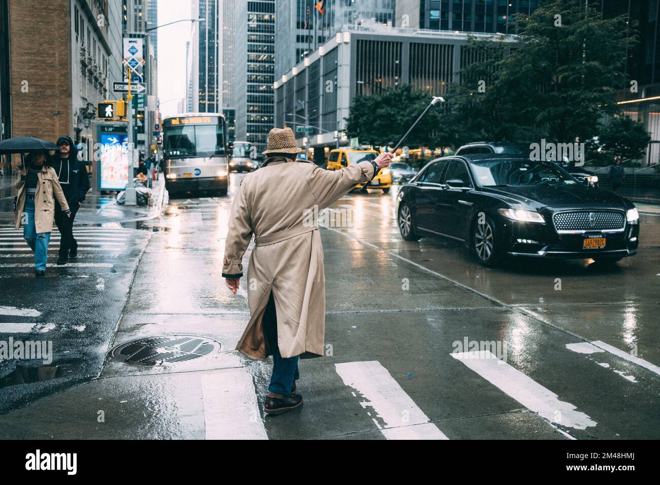 New York Manhattan, 02.10 - 10.10.22: Mann mit Trenchcoat ruft mit Hilfe  seines Gehstock nach einem Taxi. Foto: pressefoto Mika Volkmann Stock Photo  - Alamy
