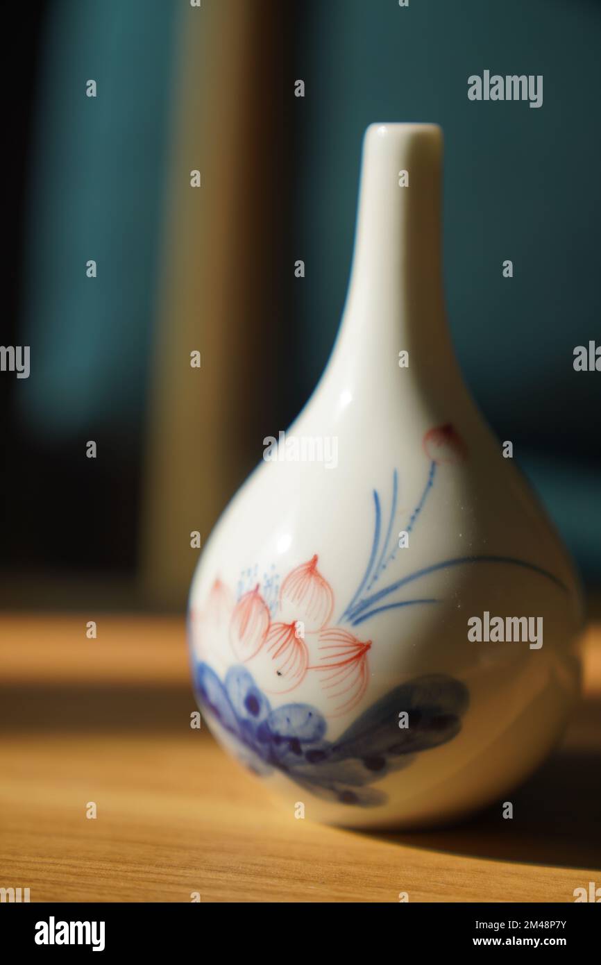 A vertical shot of a decorated porcelain vase on a table. Stock Photo