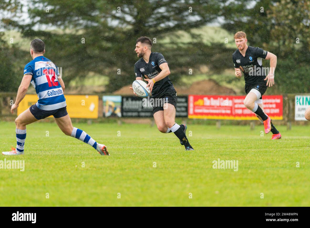 Berwick player runs with the ball in both hands advancing towards an opponent at the Berwick rugby club versus Howe of Fife rugby club mens match Stock Photo