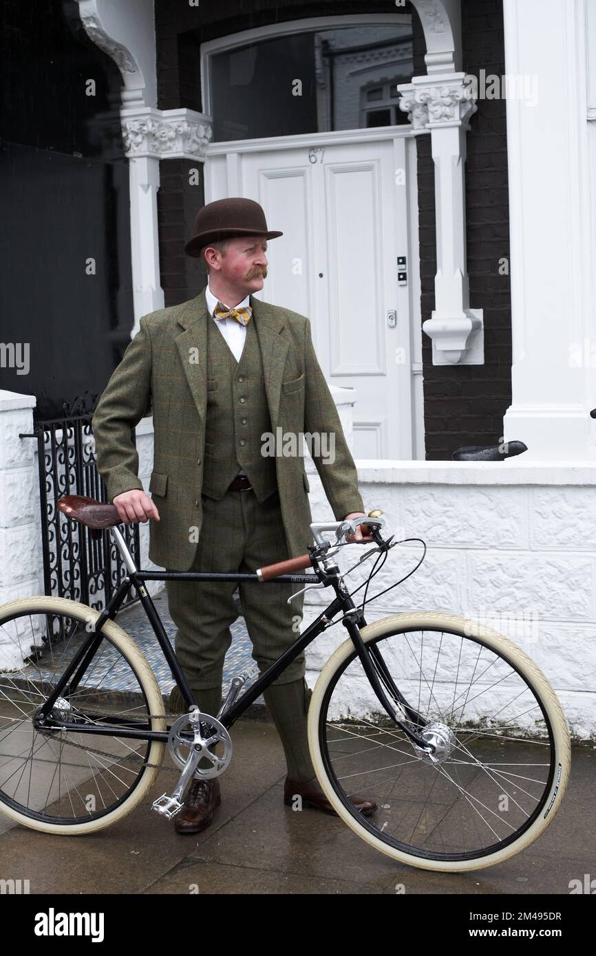 London a elegant man standing beside Pashley Guvnor bike wearing suit with bowler hat and bow tie . Stock Photo