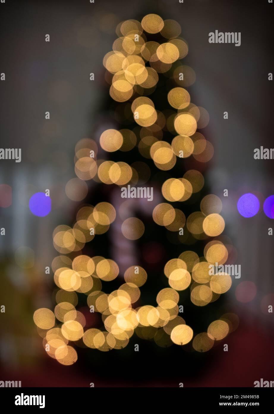Defocused Christmas tree with bokeh fairy lights glowing. Abstract blur of Christmas tree shape Stock Photo