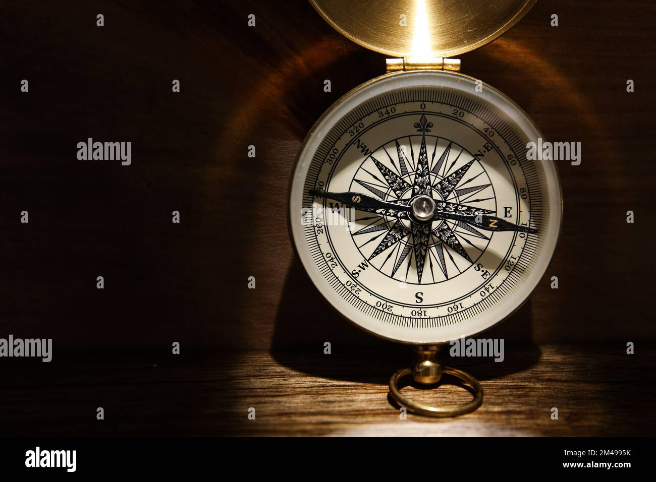 Golden compass on dark wooden background, top view Stock Photo - Alamy