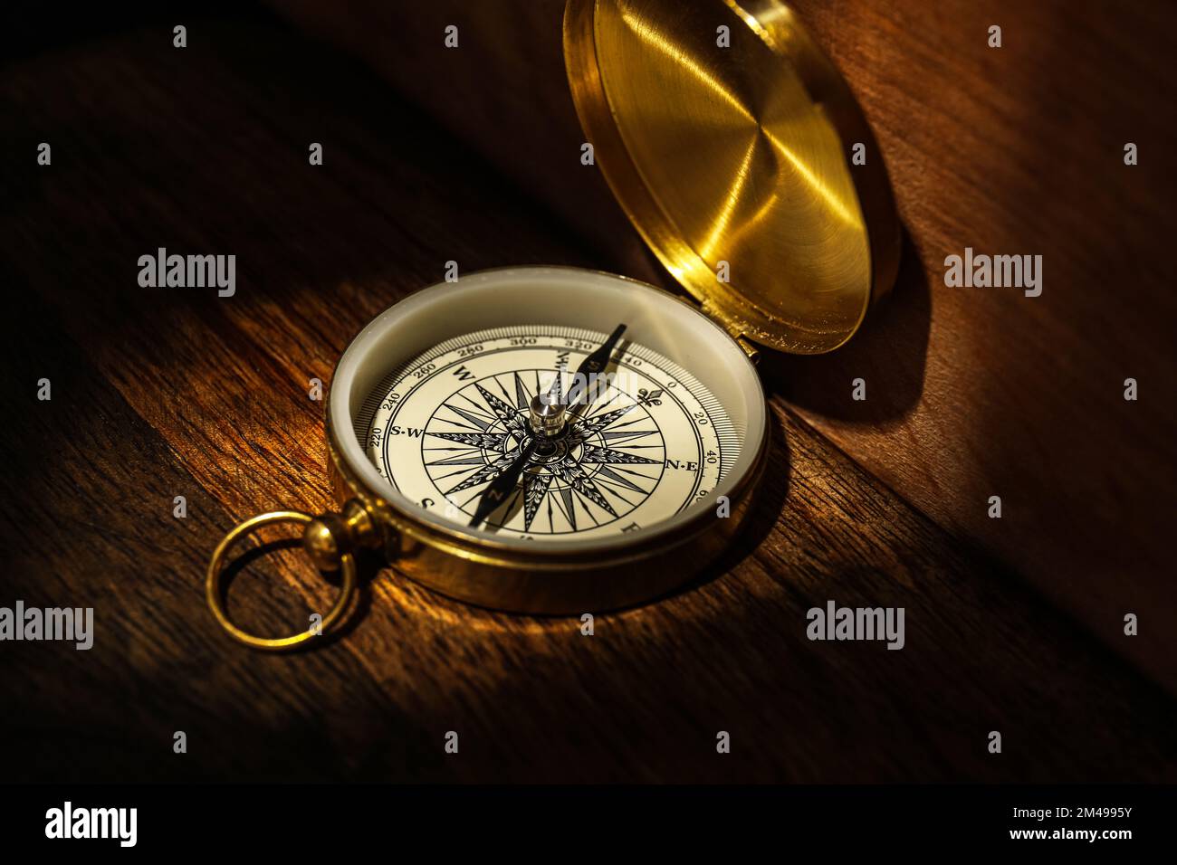 Golden compass on dark wooden background Stock Photo - Alamy