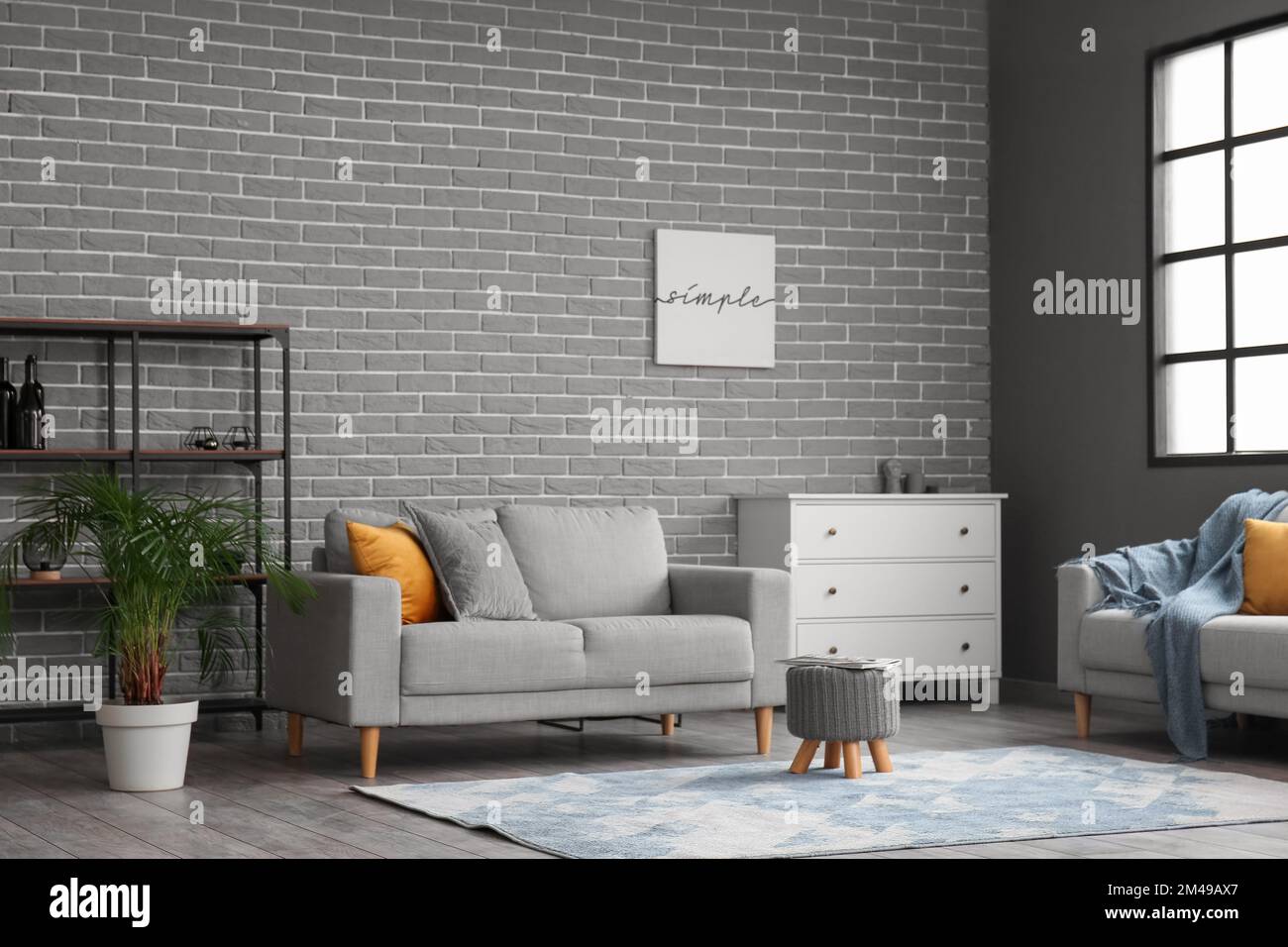 View of Stylish interior of living room with modern furniture near grey brick ...
