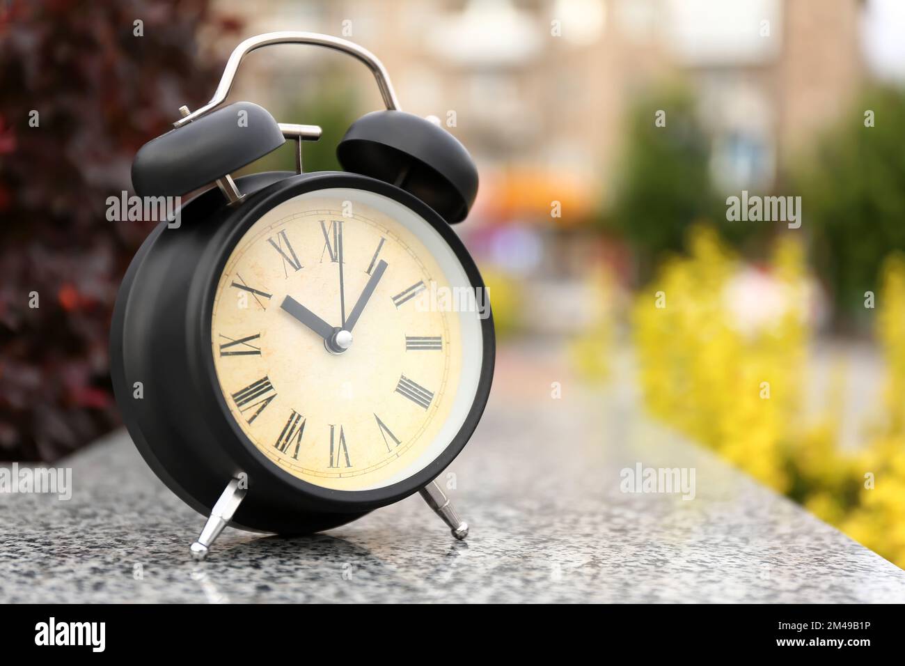 Black vintage alarm clock in park, closeup Stock Photo - Alamy