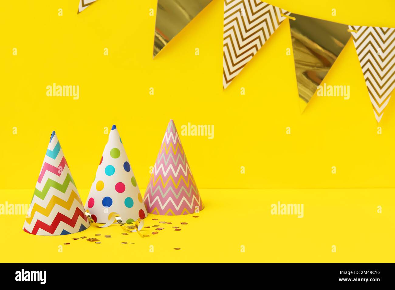 Party hats, flags and confetti on yellow background Stock Photo - Alamy