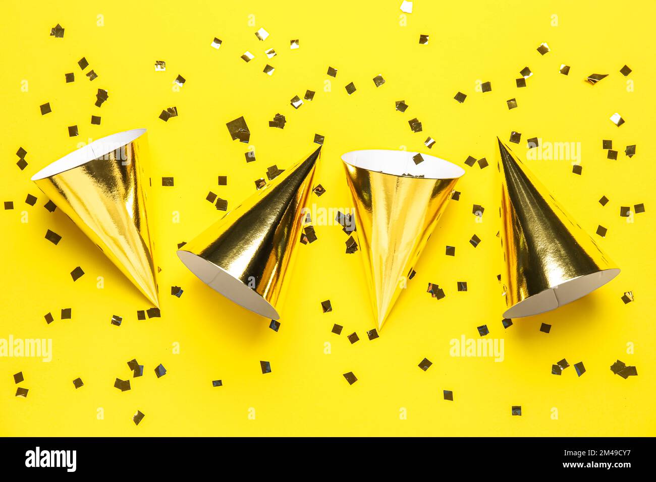 Party hats and confetti on yellow background Stock Photo - Alamy