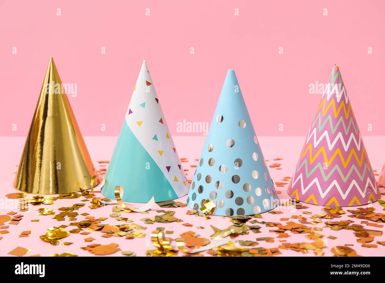 Party hats and confetti on pink background Stock Photo - Alamy