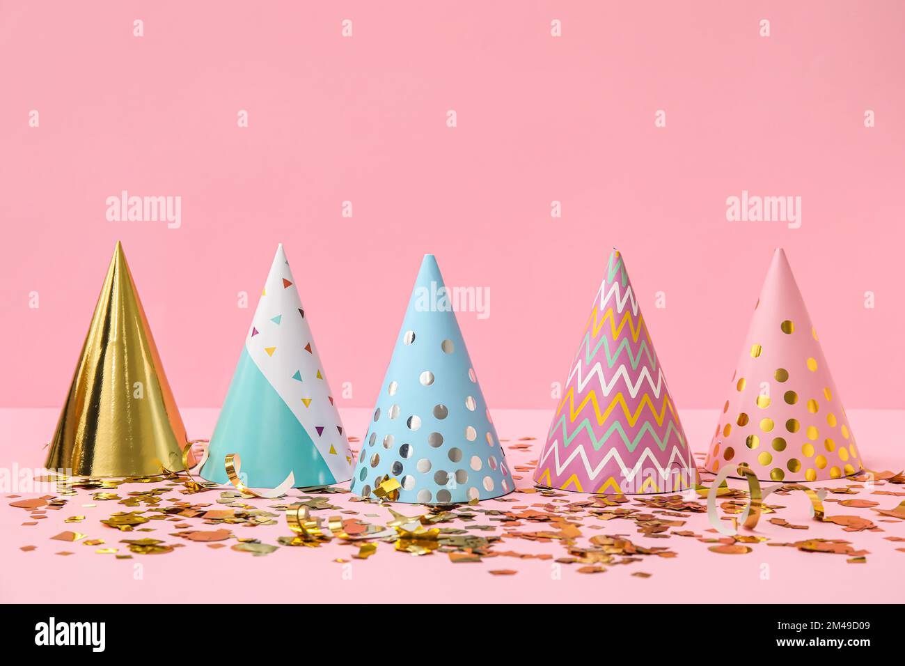 Party hats and confetti on pink background Stock Photo - Alamy