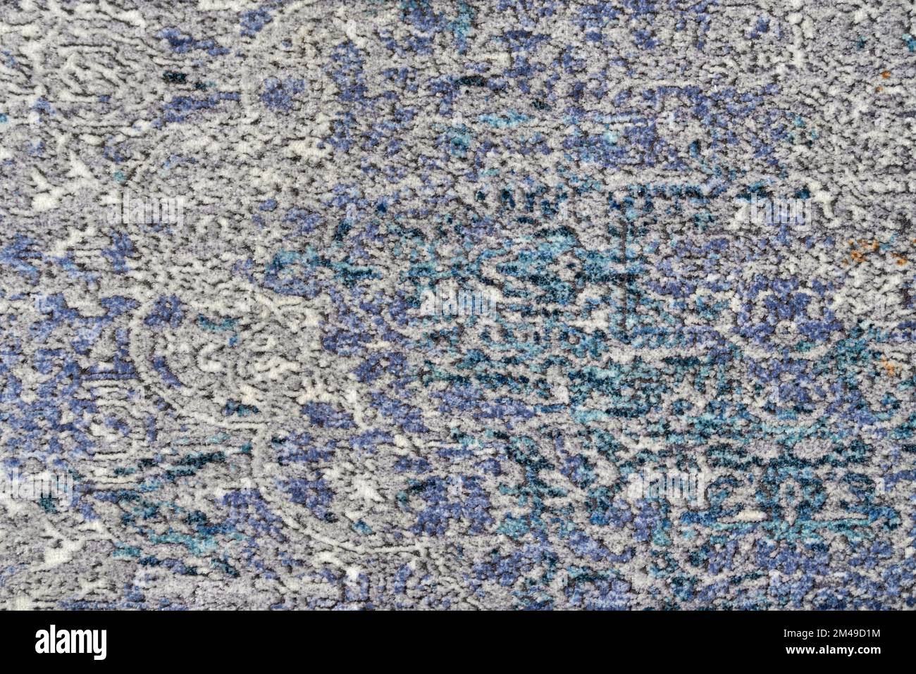 Texture of abstract, decorative velours multi-colored carpet fabric background. Close up of beautiful old blue and beige pile rug with barely visible pattern. Concept of background and textures. Stock Photo