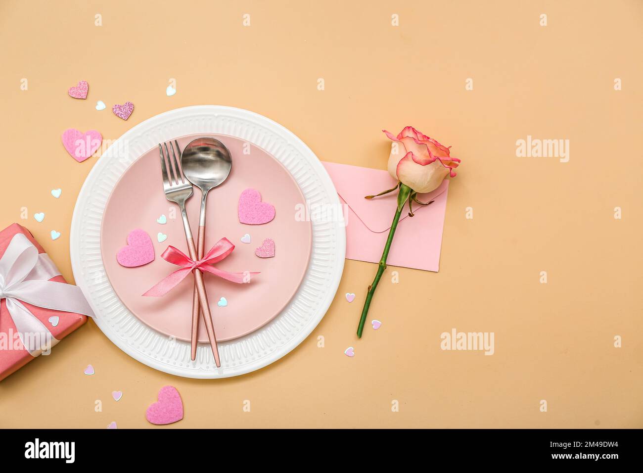 Table setting for Valentine's Day with pink rose, envelope and gift on ...