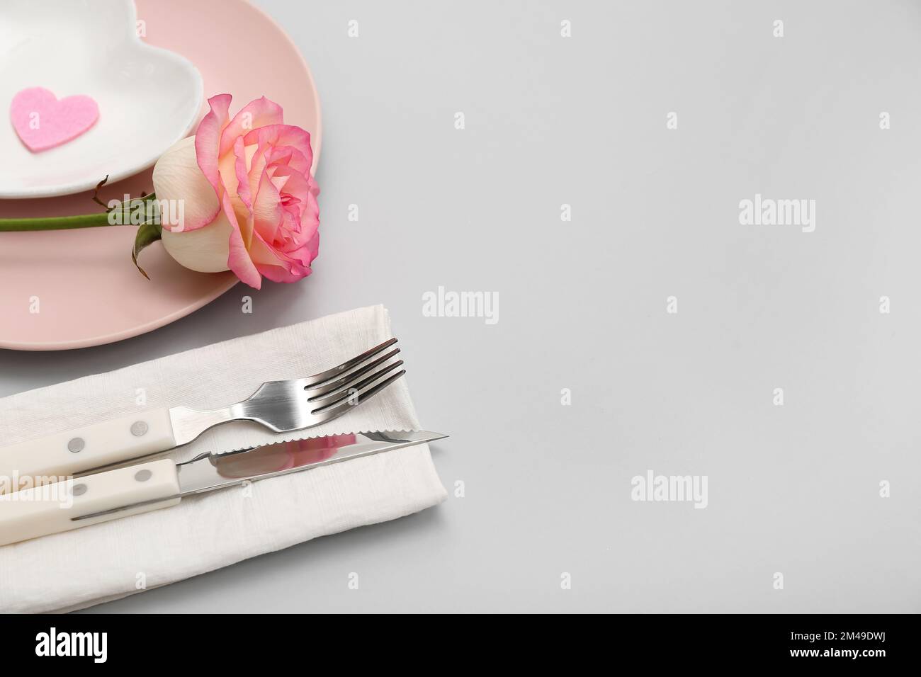 Table setting for Valentine's Day with pink rose on grey background ...