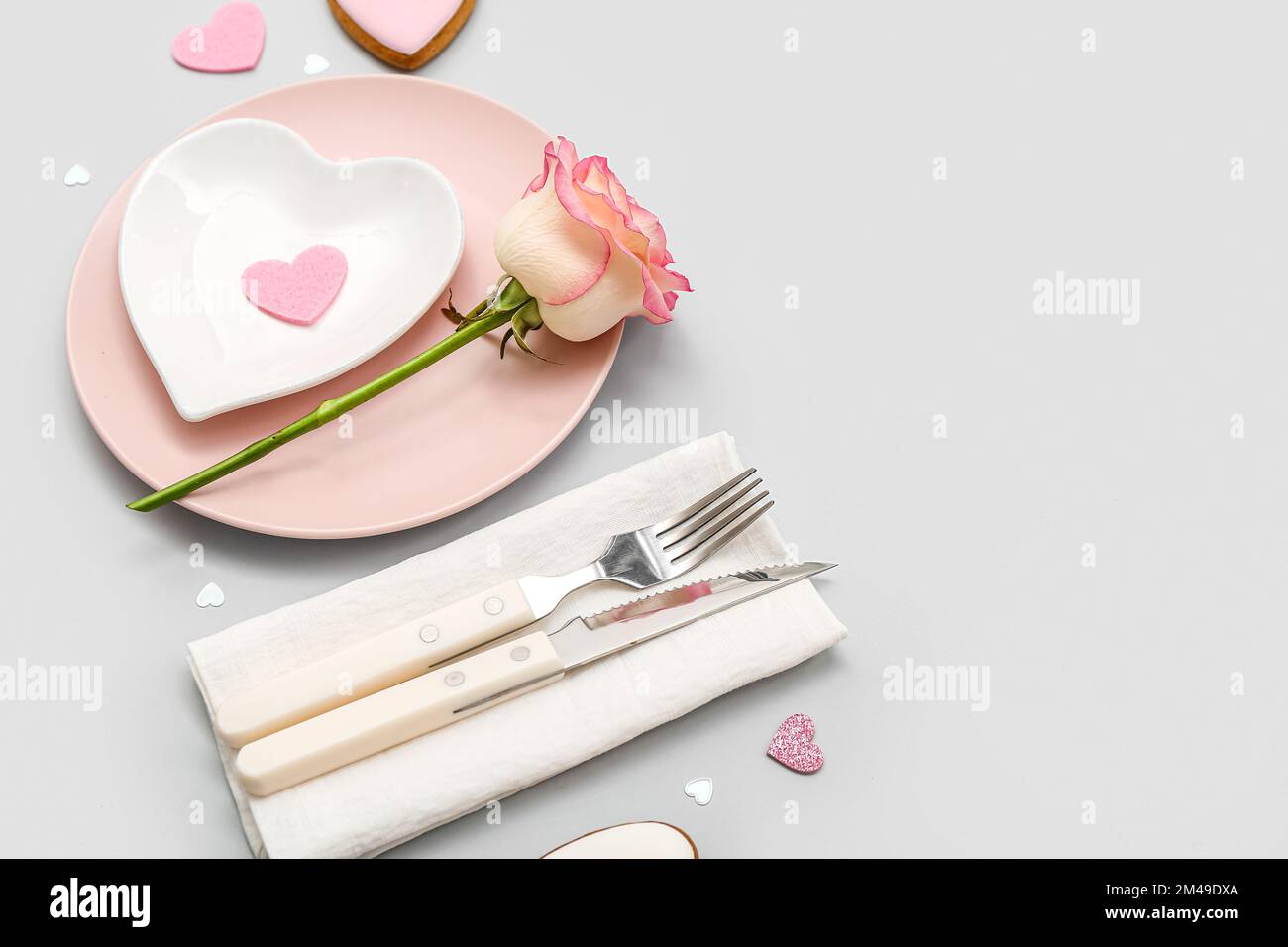 Table setting for Valentine's Day with pink rose on grey background ...
