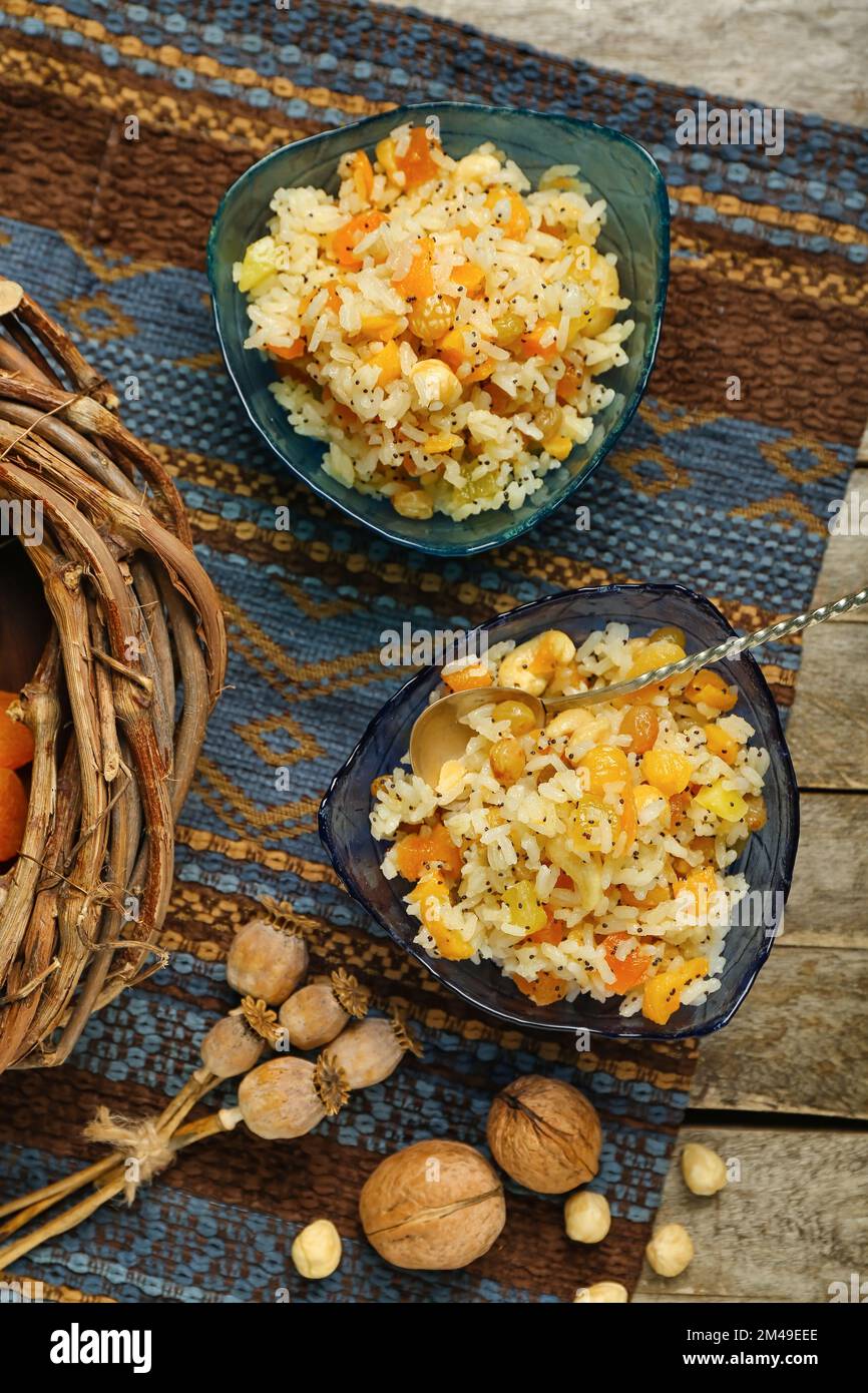 Bowls of rice Kutya, poppy pods and napkin on wooden table, top view ...