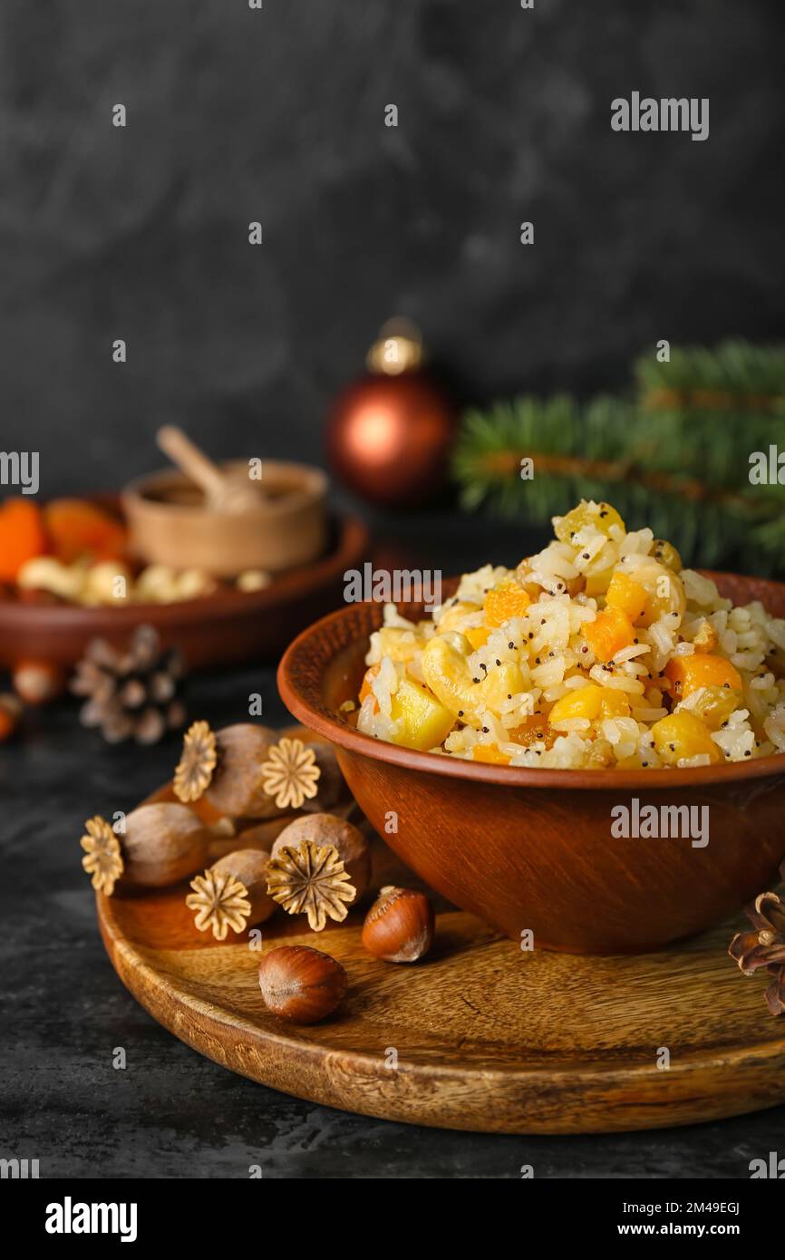 Board with bowl of rice Kutya, nuts and poppy pods on dark table ...