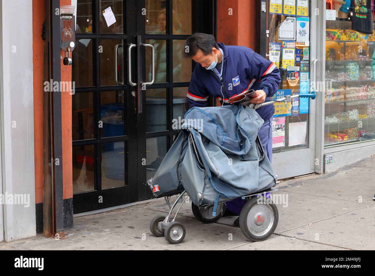 A USPS letter carrier with a satchel mail cart in New York City Stock