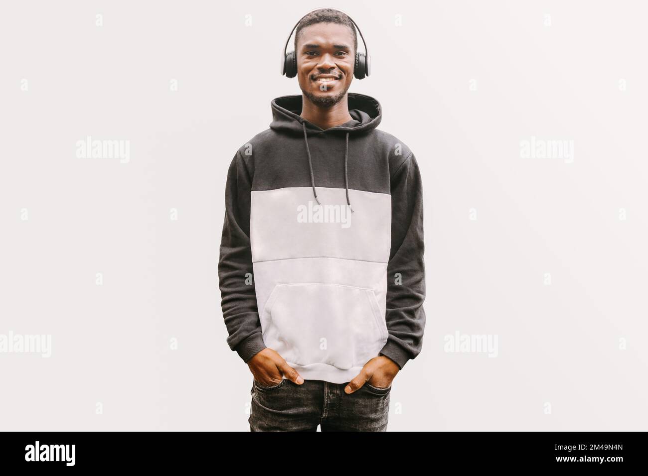 Smiling black man listening to music looking at camera over white backdrop. Relaxed confident African man in wireless headphones enjoying songs Stock Photo