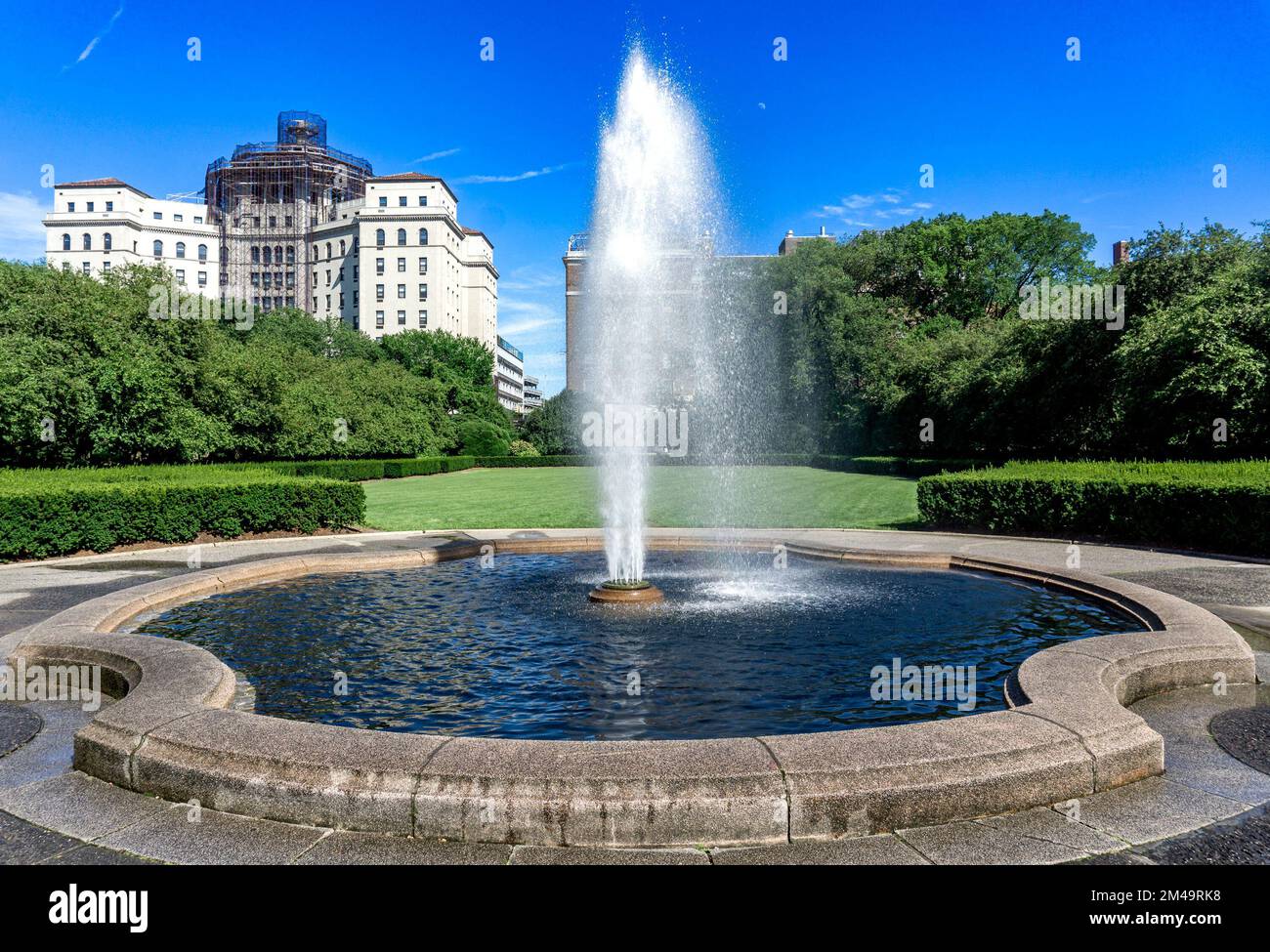 New York, NY - USA - July 20, 2018 View of Conservatory Garden's single central fountain jet in front of the symmetrical lawn, part of the formal gard Stock Photo