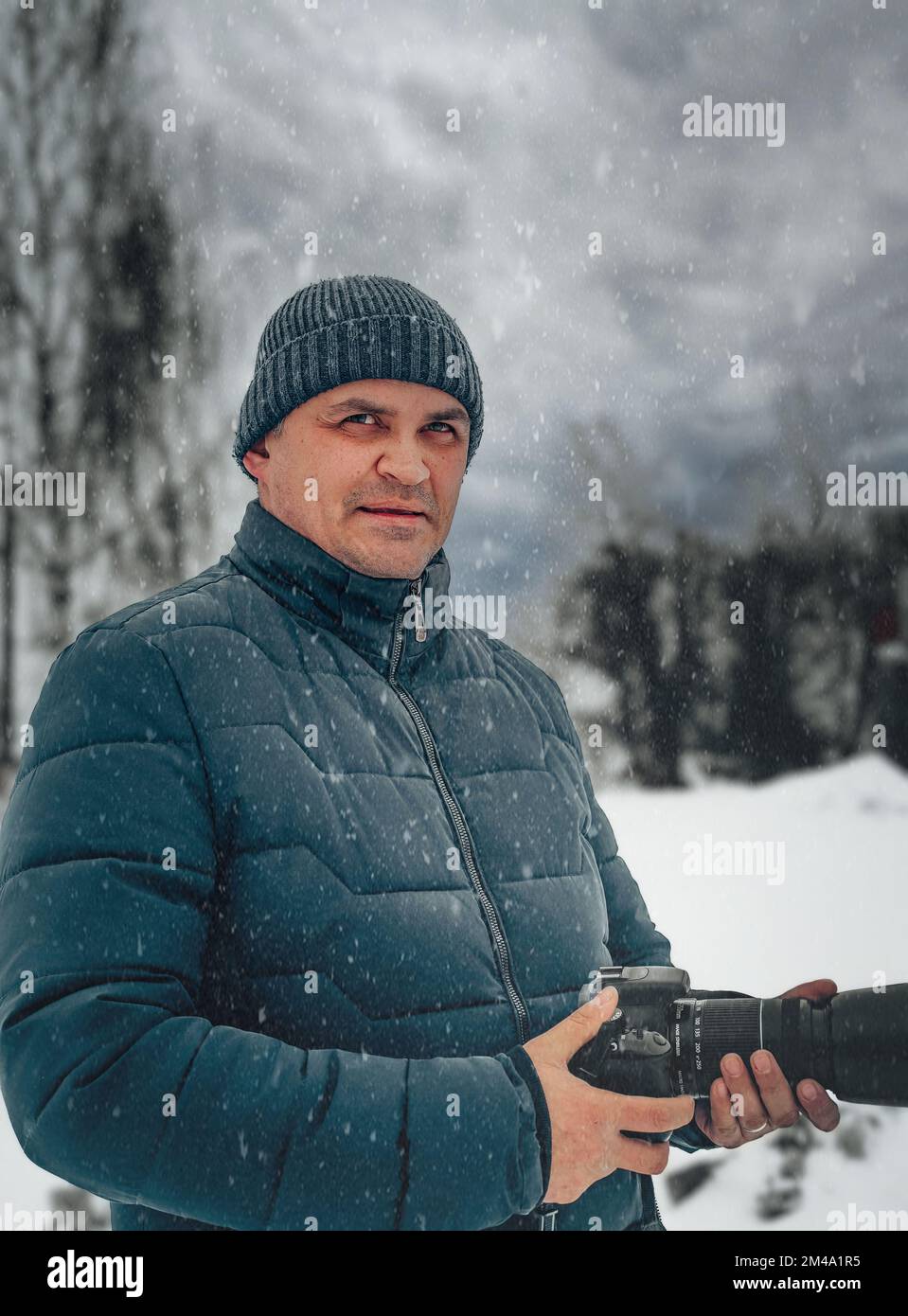 a man stands on the street in winter and holds a camera in his hands Stock Photo