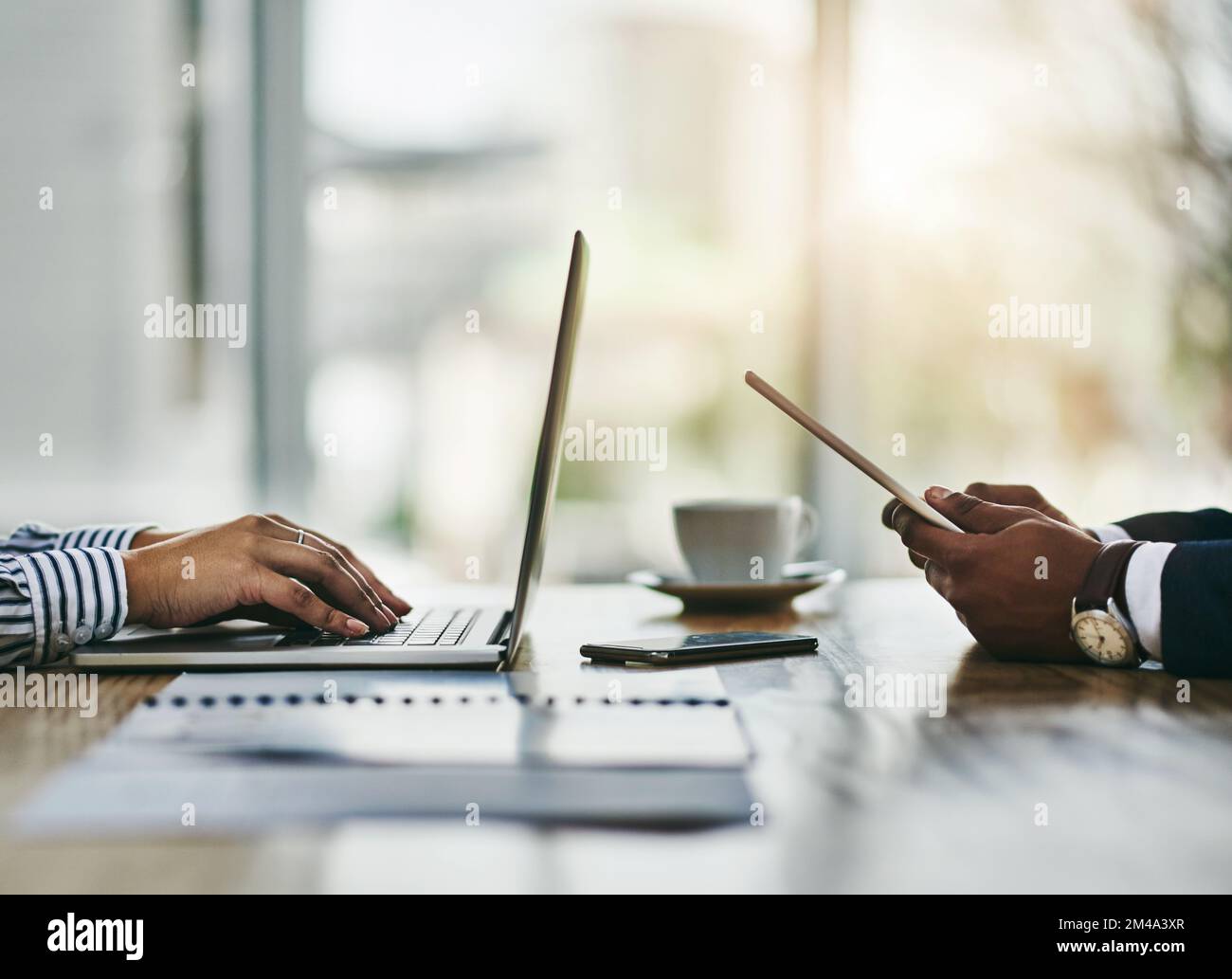 Business cant survive without modern technology. Closeup shot of two businesspeople using digital devices during a meeting in an office. Stock Photo