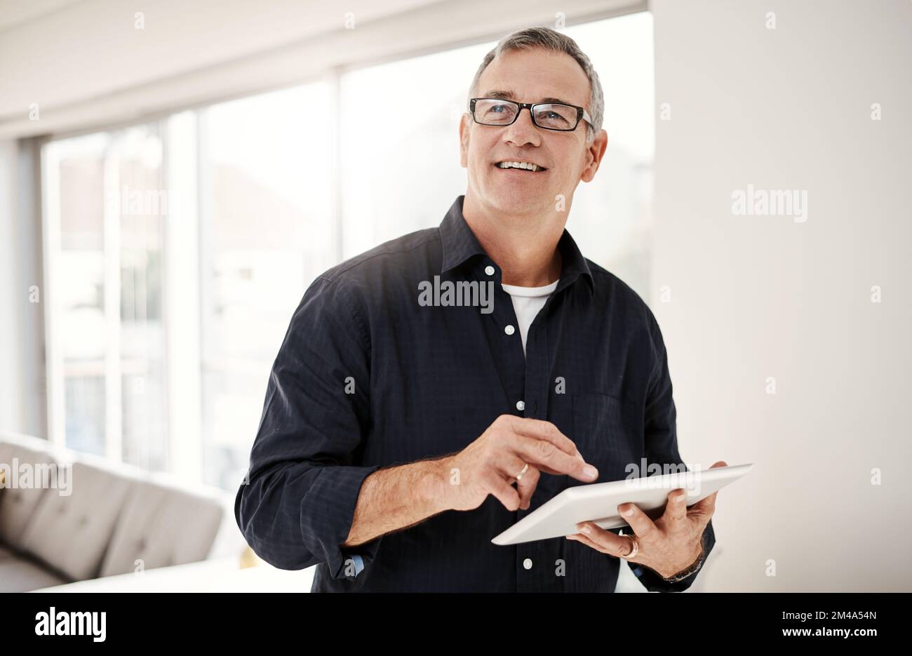 What a blessing mobile technology has become. a mature man using a digital tablet at home. Stock Photo