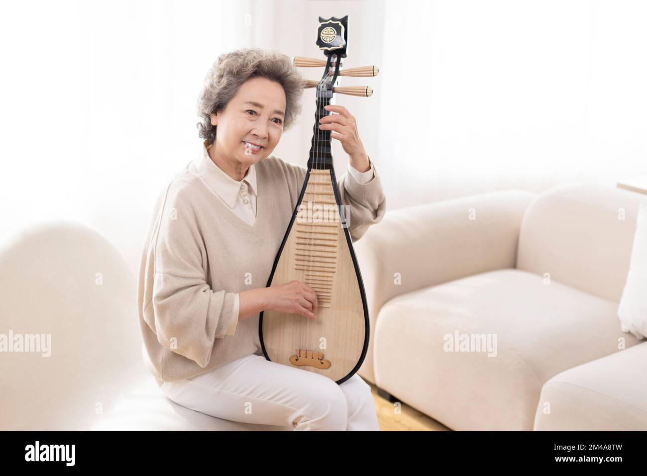 Senior Chinese woman plucking lute Stock Photo