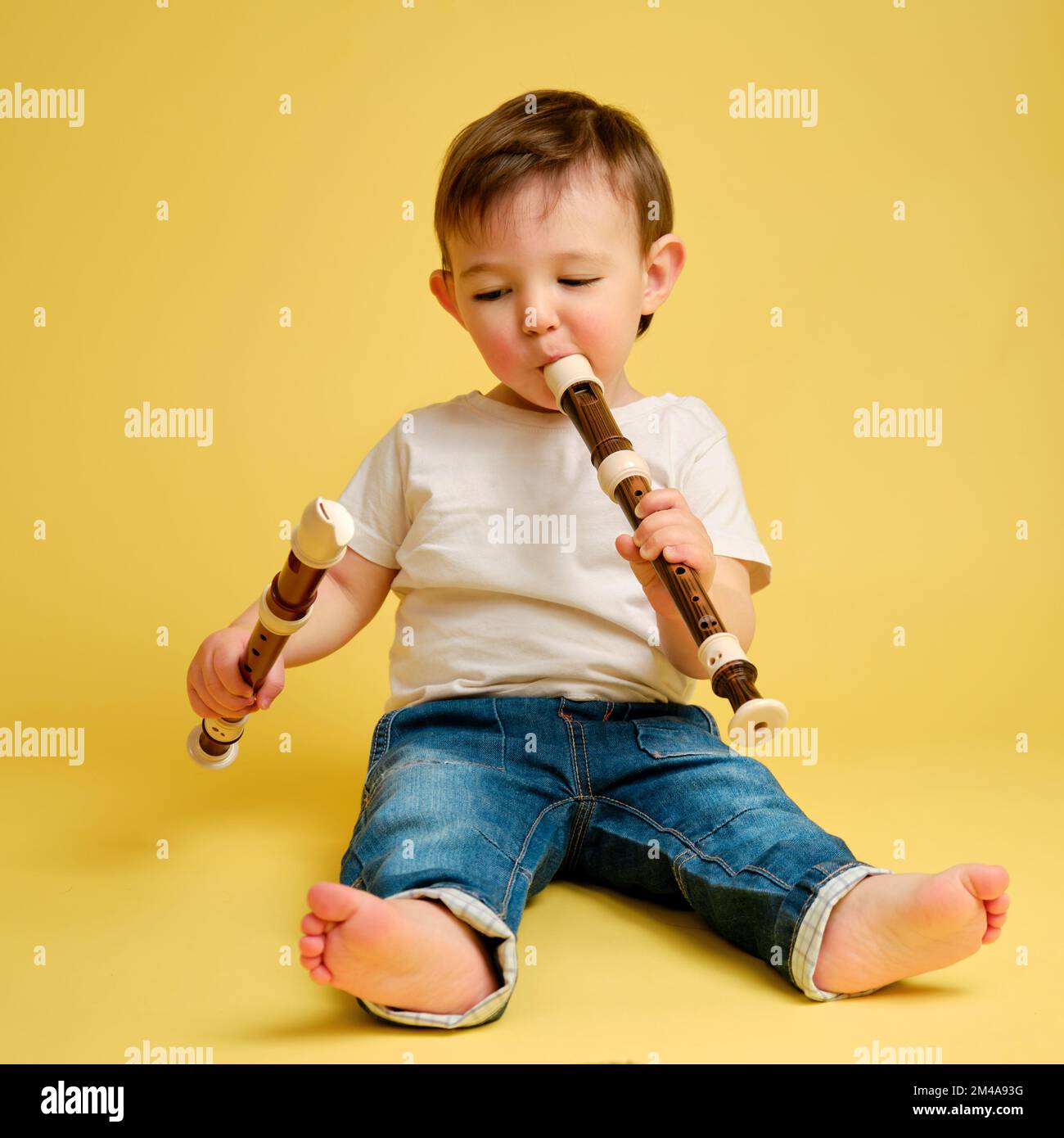 Toddler baby plays the flute, a child with a wind musical instrument on