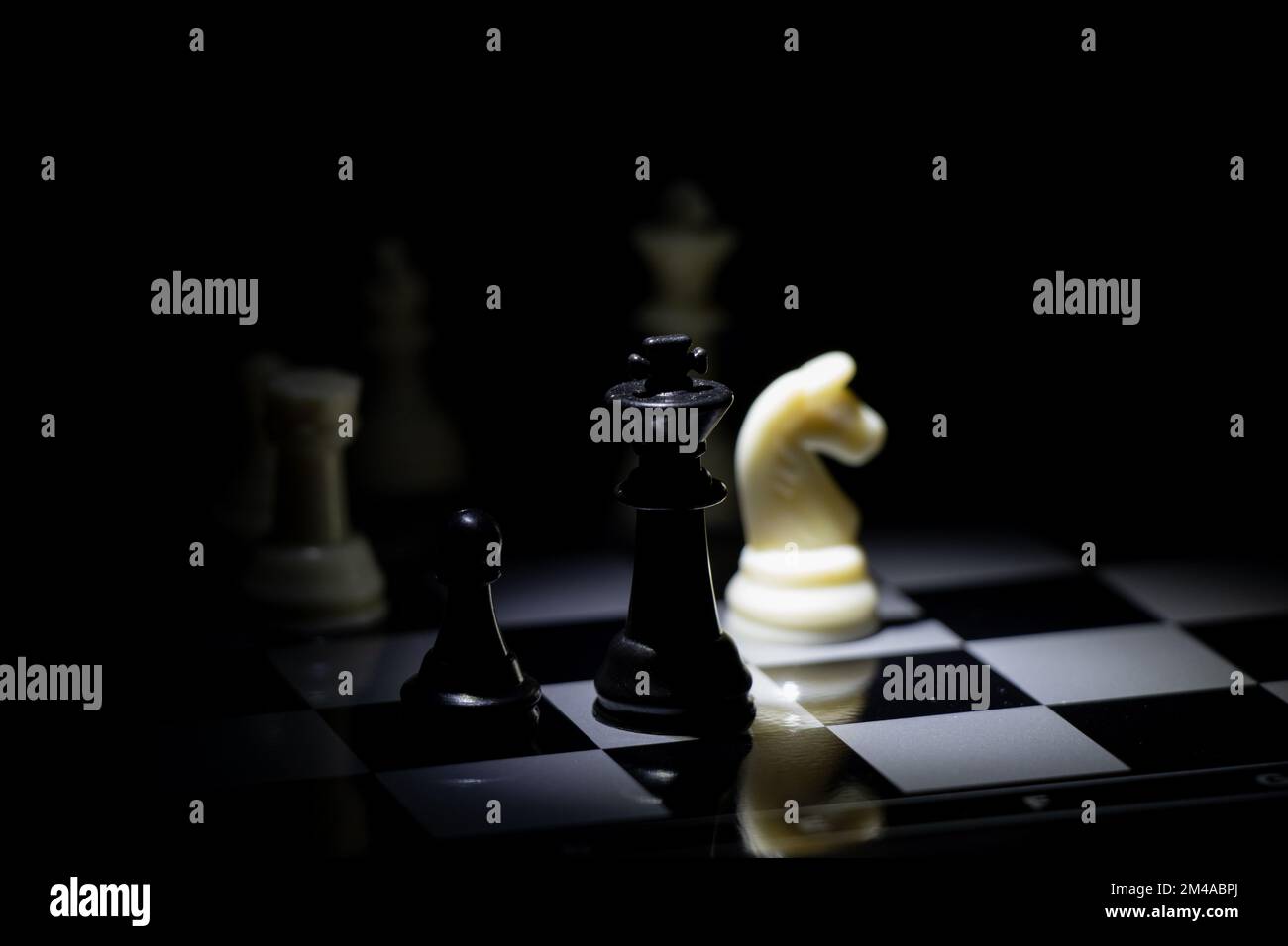 chess pieces on a chessboard in a dark room illuminated by a lantern ...