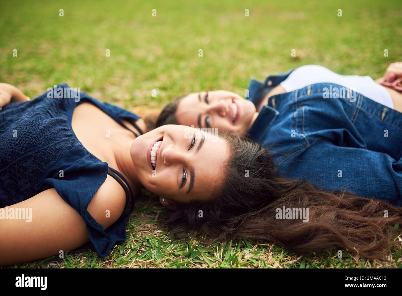 Our friendship is forever. two female best friends lying on the grass in a public park. Stock Photo