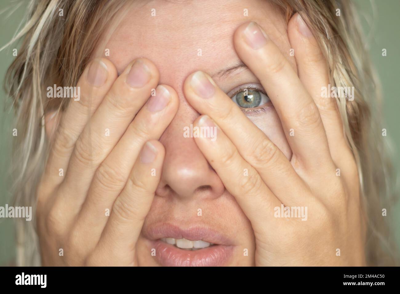young girl covered her face with hands closeup portrait on an isolated background Stock Photo