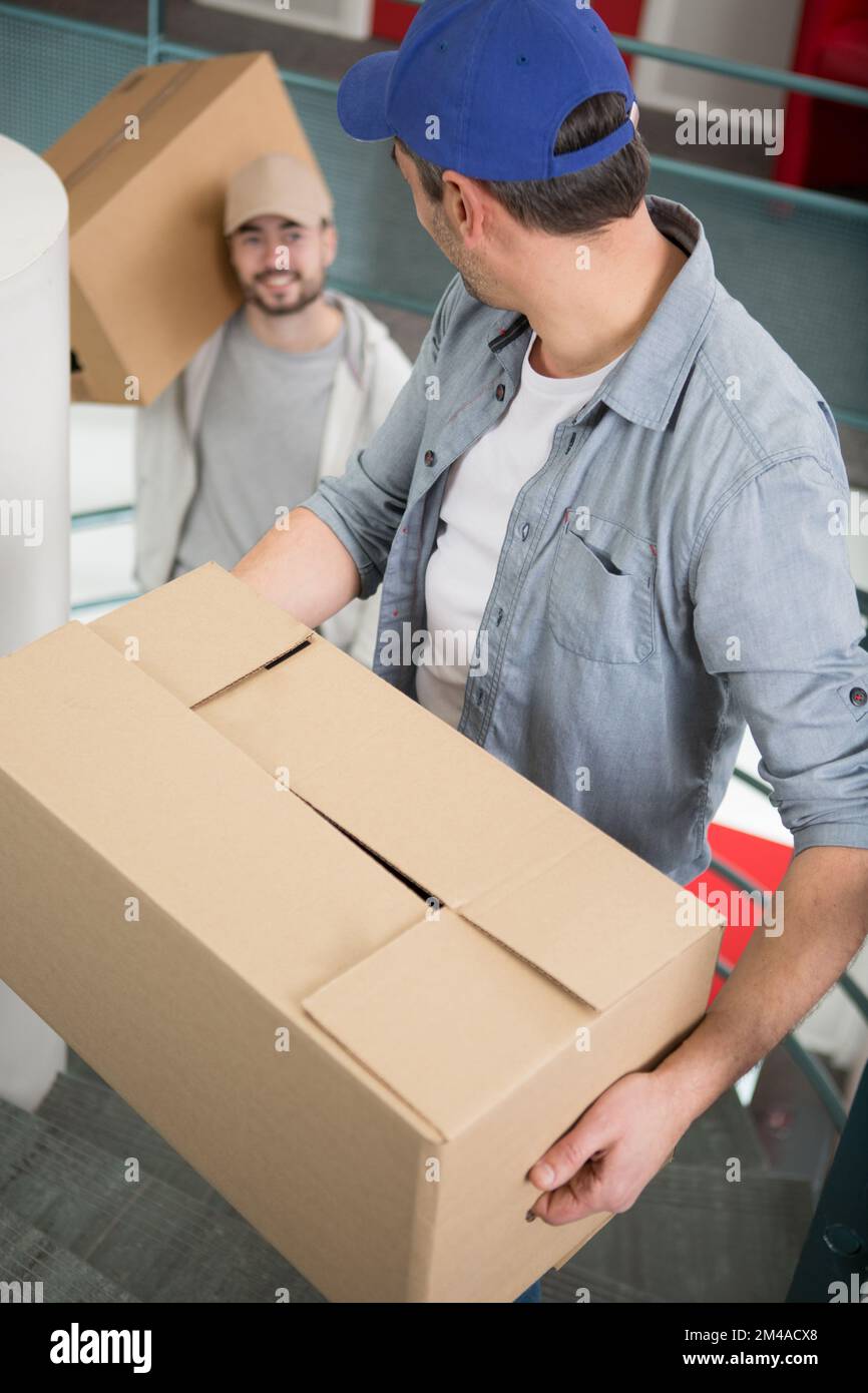two men carrying cardboard boxes on staircase Stock Photo Alamy
