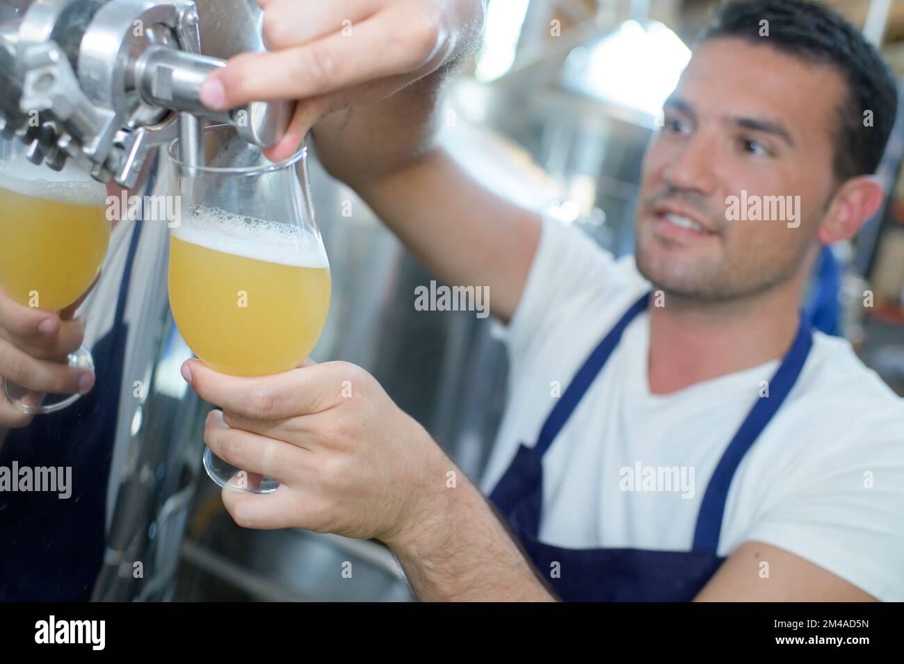 worker in brewery pouring glass of beer from vat Stock Photo Alamy